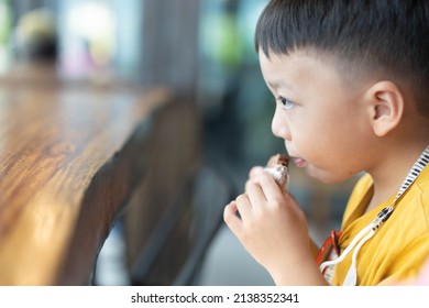 Cute Little Asian Toddler Boy Child Holding Cookie And Eating Cookie In Cafe Bakery Shop.Hungry Toddler Boy Make Delicious Face When He Eating Cookies.biscuit Morning.chocolate Cookie.homemade Bakery.