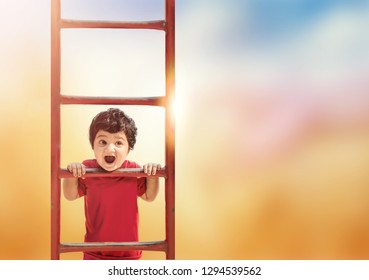 Cute Little Asian/Indian Child Making Funny Faces, Playing At Kid Play Ground Looking At Camera And Climbing Up Iron Ladder.