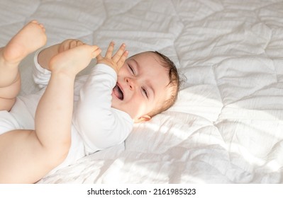 Cute Little Baby Boy Is Crying. Toddler On Bed, White Blanket,sunny Rays, Morning Situation.motherhood. Teething Period,bloating Belly Pain, Want To Sleep,eat, Hungry Child