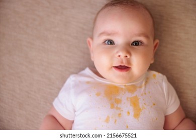 Cute Little Baby Boy Lying On The Couch All Stained With Porridge, Smiling And Making Funny Faces After Meal