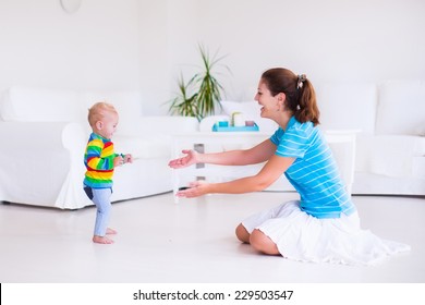 Cute Little Baby Boy Making His First Steps, Walking To His Mother In A White Sunny Living Room