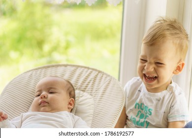 Cute little baby boy with newborn sister. Toddler kid meeting new born sibling. Infant sleeping in white bouncer under a blanket. Kids playing and bonding. Children with small age difference.