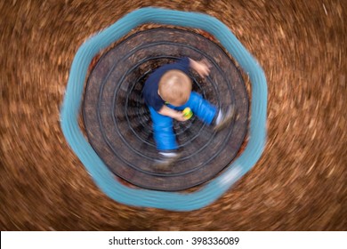 Cute Little Baby Boy Sitting On A Small Carousel Turning Around Fast