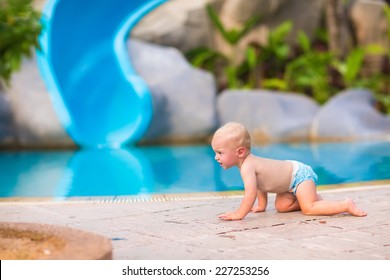 Cute little baby boy in a swimming diaper crawling at pool side having fun during summer vacation in a beautiful tropical resort