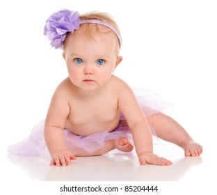 Cute little baby girl with big blue eyes wearing a tutu and flower in her hair