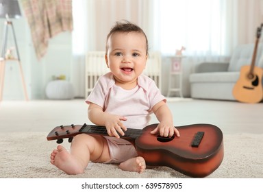 Cute little baby with guitar at home