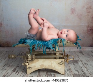 Cute Little Baby With Legs Up Lying On Child Scales On Wooden Floor