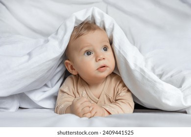 Cute little baby playing hiding under white blanket at home. - Powered by Shutterstock