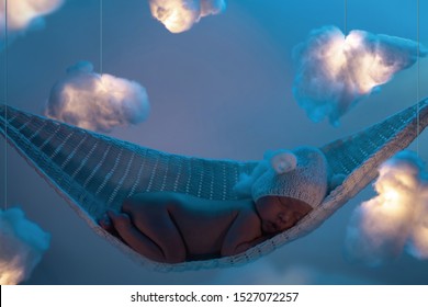 Cute Little Baby Sleeping In The Hammock With A Lot Clouds Made Of Cotton Wool