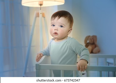 Cute little baby standing in crib at home