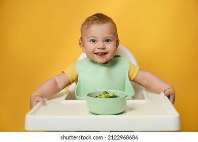 Cute Little Baby Wearing Bib While Eating On Yellow Background