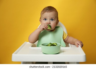 Cute Little Baby Wearing Bib While Eating On Yellow Background