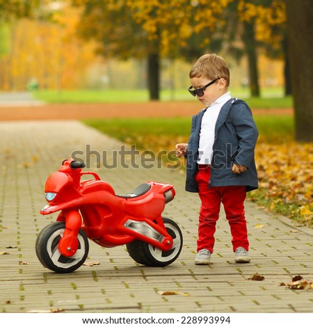 cute little biker on road with motorcycle. Young boy on toy motorcycle 