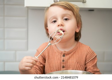 Cute Little Blond Preschool Kid Boy Baking Cake In Domestic Kitchen, Indoors. Funny Child  Tasting Sweet Dough. Little Helper