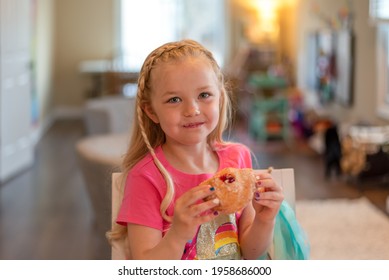 Cute Little Blonde Girl Eating A Jelly Donut