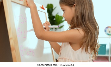 Cute little blonde girl erasing the blackboard in class with sponge. Little girl kindergarten preschool student in class.First time to school education,Childhood education concept.