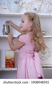 Cute little blonde girl in a pink dress with curls and a beautiful hairstyle