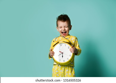 Cute little boy with alarm clock,isolated on blue. Funny kid shouting joyfully pointing at alarm clock at morning. Excited boy overslept before school. People, school, time and lifestyle concept