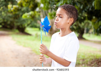 cute little boy blowing on a pinwheel - Powered by Shutterstock