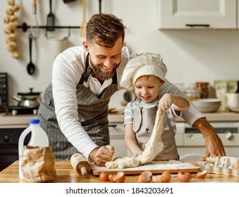 Cute little boy in chef hat and apron kneading dough with help of father while preparing pie together in cozy home kitchen
 - Powered by Shutterstock