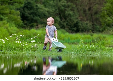 Cute little boy with a children's wheelbarrow on the shore of a forest lake, Vysočina Czech Republic - Powered by Shutterstock