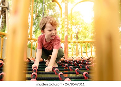 cute little boy climbing on net robes on playground in schoolyard. happy and enjoy adventure sports play alone outdoor playground - Powered by Shutterstock