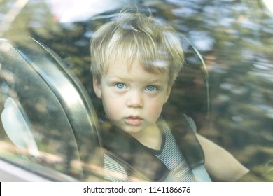 Cute Little Boy Close Up Portrait Through The Car Window Glass.