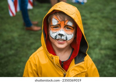 cute little boy with colorful painted face like tiger. funny face. child in the yellow raincoat. - Powered by Shutterstock