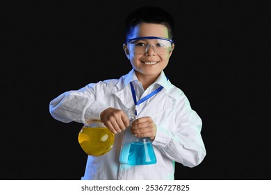 Cute little boy conducting experiment with chemical flasks on black background - Powered by Shutterstock