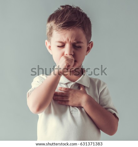 Cute little boy is coughing, on gray background