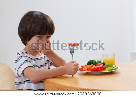 Cute little boy covering mouth and refusing to eat vegetables at home [[stock_photo]] © 