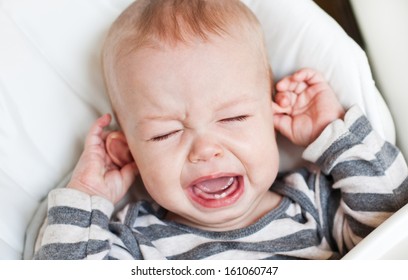 cute little boy crying and holding his ear on a white background