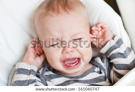 cute little boy crying and holding his ear on a white background