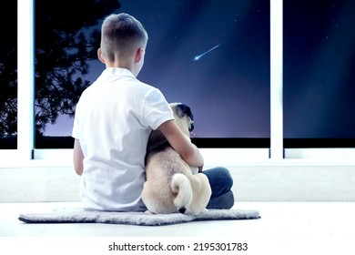 Cute Little Boy With Dog Sitting Near Window And Looking At Shooting Star In Beautiful Night Sky