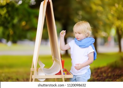 Cute little boy drawing with colorful paints in summer park. Creative child painting on nature. Outdoors activity for toddler kid. Talented toddler painter - Shutterstock ID 1120098632