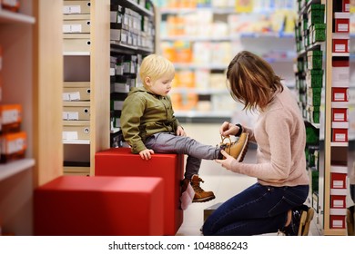 Cute Little Boy During Shopping With His Young Mother. Kid Trying New Fashion Seasonal Shoes. Child In Shopping Center/mall Or Baby Apparel Store.