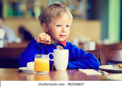 Cute Little Boy Eating Breakfast In Cafe