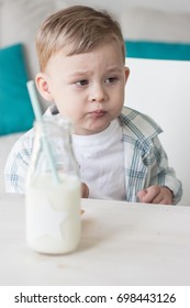 A cute little boy is eating candy and drinking milk. Health. Happy child. Breakfast. A little boy is sitting at the table.