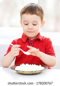 Cute Little Boy Is Eating Cottage Cheese Using Spoon