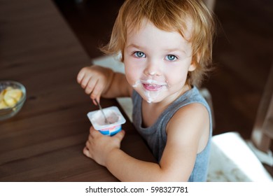 Cute little boy eating yogurt.
