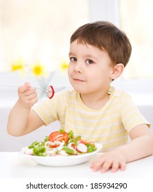 Cute little boy eats vegetable salad using fork - Shutterstock ID 185934290