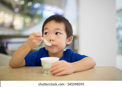 Cute little boy enjoying ice cream in cafe.