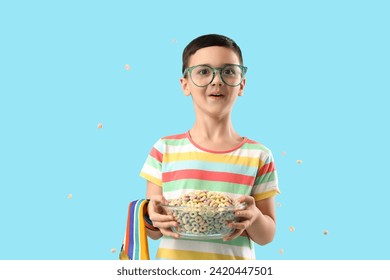 Cute little boy in eyeglasses with bowl of cereal rings on blue background - Powered by Shutterstock