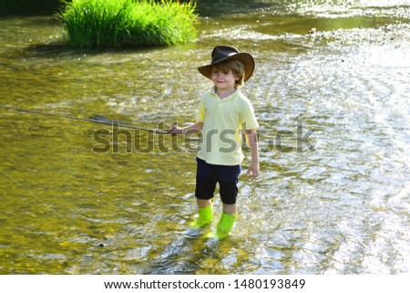 Cute little boy fishing on pond. Young man fly fishing. Photo of little boy fishing. Boy in yellow shirt with a fishing rod by the river