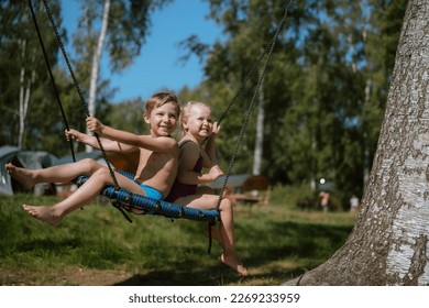 cute little boy and girl having fun on a spiderweb tree swing at playground. Summer vacation in the nature. - Shutterstock ID 2269233959