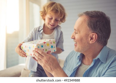 Cute Little Boy Is Giving His Grandpa A Gift And Smiling