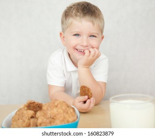 Cute Little Boy Is Having A Breakfast. Child Eating Cookies And Drinking Milk.