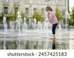 Cute little boy having fun with water in city fountain. Child playing water games outdoors on hot day. Summer activities for small children.
