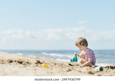 Cute little boy having fun on a sandy beach on warm and sunny summer day. Kid playing by the ocean. Summer activities for children. - Powered by Shutterstock