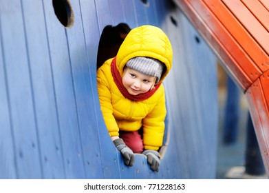 Cute little boy having fun on outdoor playground. Spring, autumn or winter active leisure for kids.